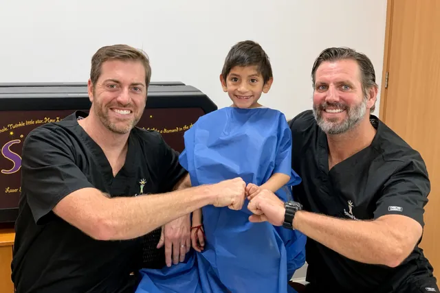 Two SpineHope surgeons fist-bump a young patient